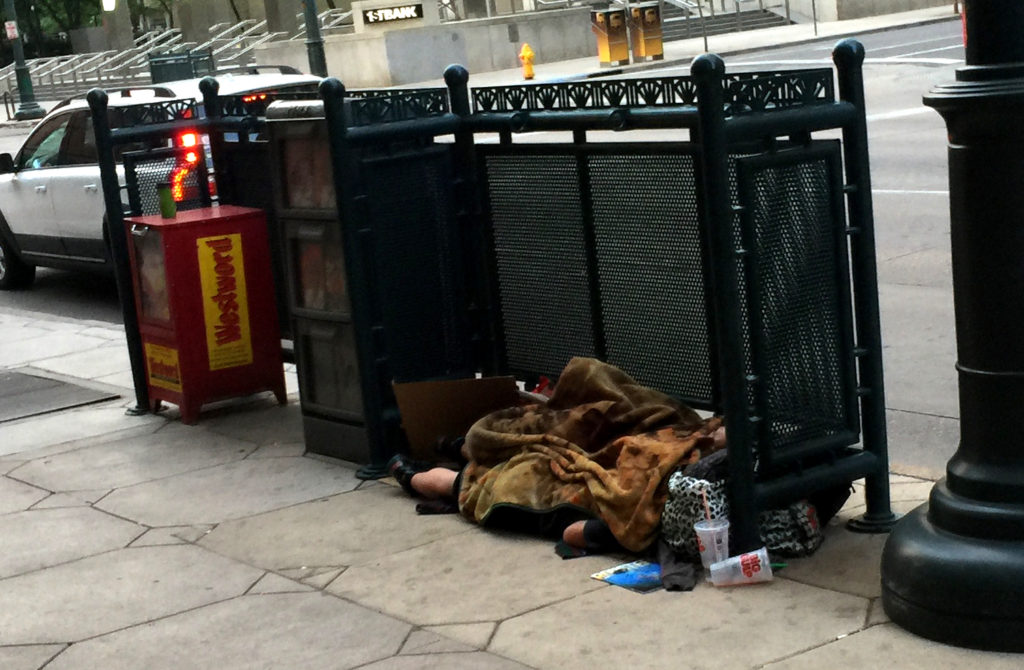 Homeless man sleeping on the sidewalk; 17th and Stout, Denver