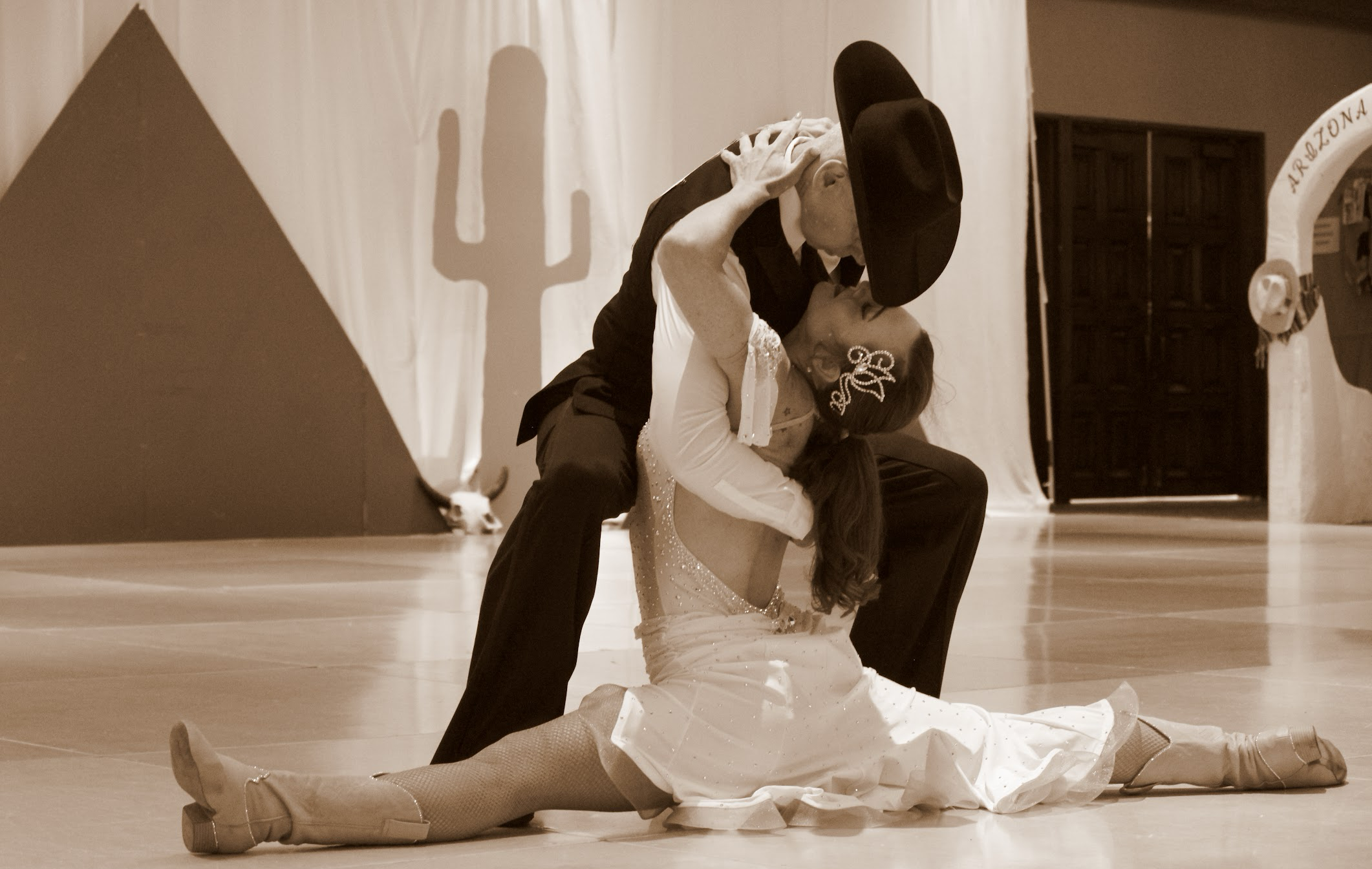 Ballroom dancers performing a dramatic dip at a Western-themed dance competition